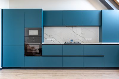 Contemporary kitchen featuring a gas stove, matte blue cabinets, and a striking marble backslash. A perfect balance of utility and elegant design.